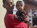 Avi holding his baby sister at home