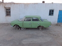 Green car in front of white building