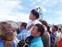 Mongolian man lifting up his son to watch the wrestling at naadam