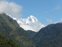 White mountain sticking up behind green mountain